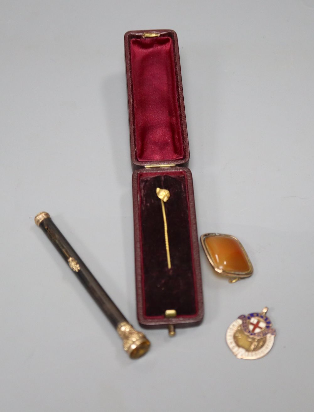 An early 20th century gold plate mounted propelling pencil, an agate set brooch, a 9ct gold and enamel medallion and a fox head pin.